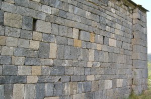 Muro con paramento de piedra vista y vanos pequeños.